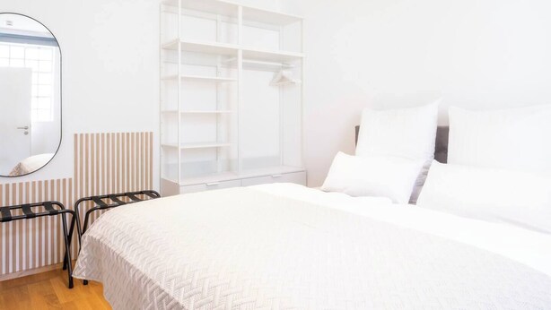 Ein Schlafzimmer mit Bett, Schrank, Heizkörper und Spiegel.