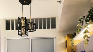 Un interior moderno con un televisor sobre un estante de madera, una mesa redonda con un jarrón y un par de puertas correderas.