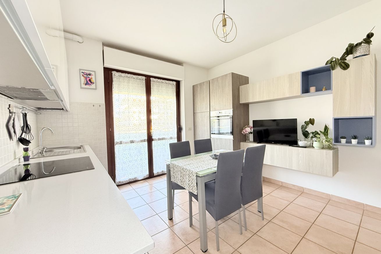 A modern kitchen with a dining area, a built-in oven, and a TV.