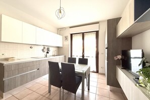 Una cocina moderna con comedor, televisor y ventana con cortinas.