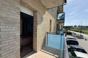 A building with a brick exterior, a glass balcony, and a parking area with cars. - SE272 - Senigallia, new fully equipped one-bedroom apartment with private garage (Senigallia)