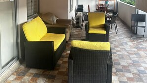 Katettu terassi, jossa on rottinkihuonekaluja, ruokailutila ja näkymä kaupunkiin.