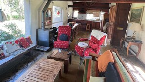 A cozy interior with wooden beams, a sofa, chairs, a table, and a kitchen area.