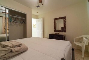 A bedroom with a bed, a dresser, a mirror, a chair, and a closet. - Ko Olina - 6BR Condos - Sleeps 16 (Kapolei)