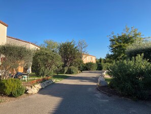 A residential street with houses, trees, and a clear sky. - Quiet, Air-Conditioned Bastidon in a Residential Complex with a Pool (Aubignan)
