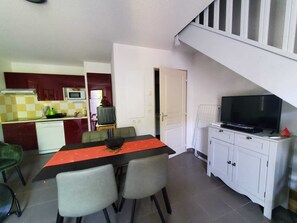 A compact kitchen with a dining area, a TV, and a staircase. - Quiet, Air-Conditioned Bastidon in a Residential Complex with a Pool (Aubignan)