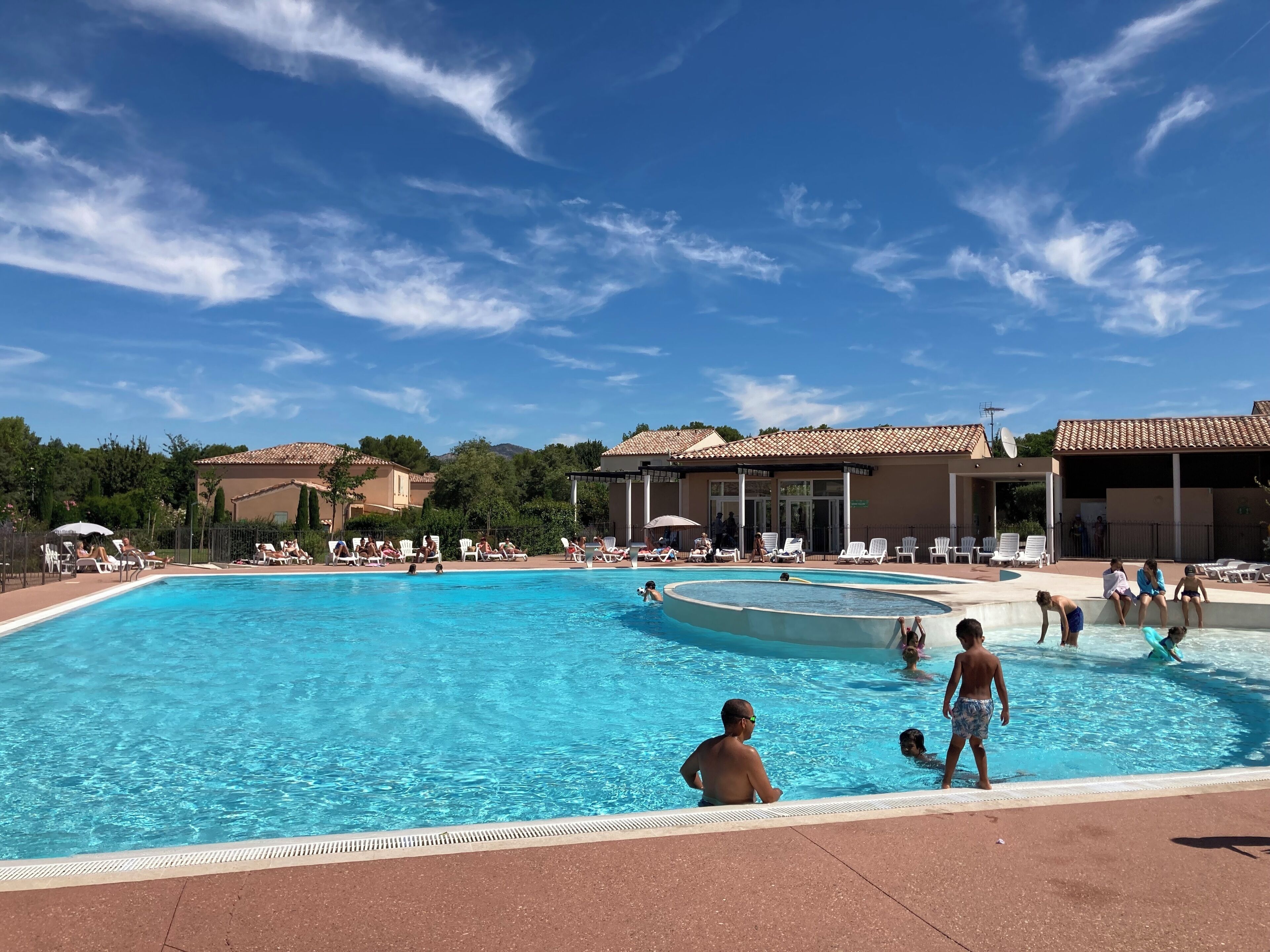 A swimming pool with lounge chairs and a building in the background.