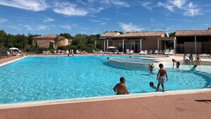 Ein Schwimmbecken mit Liegestühlen und einem Gebäude im Hintergrund.