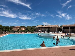 A swimming pool with lounge chairs and a building in the background. - Quiet, Air-Conditioned Bastidon in a Residential Complex with a Pool (Aubignan)