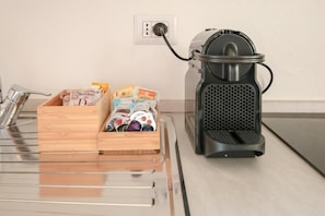A kitchen with a coffee maker, a wooden box with snacks, and a power outlet. - Quattro Stanze Alle Quattro Vie (CREMA)