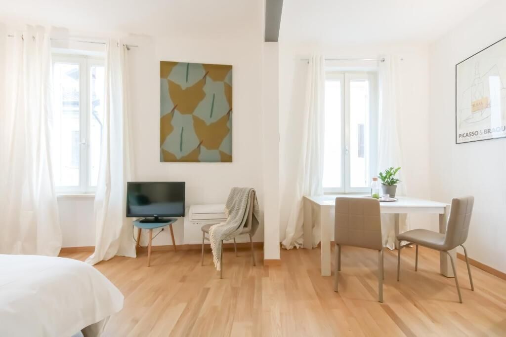 Une chambre d’hôtel comprenant un lit, un bureau avec une chaise, un téléviseur et une œuvre d’art accrochée au mur.