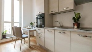 Cocina moderna con comedor, que incluye una mesa, sillas y un ventanal con plantas.