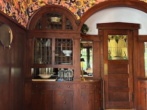 A wooden cabinet with glass doors, a door with a stained glass window, and a floral wallpaper ceiling. - Large Luxury Home*Spa Suite*Chef's Kitchen*Bunk Rm (Milwaukee)