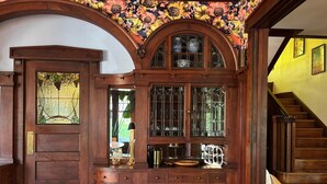 Um armário de madeira com portas de vidro, uma escadaria e um papel de parede com padrão floral.