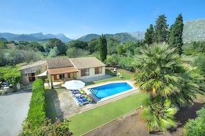 A house with a swimming pool, a patio with lounge chairs, and a view of mountains. - Villa Almedra Boi in Pollensa for 2 with Garden, Pool, Wi-Fi & A/C (Pollença)