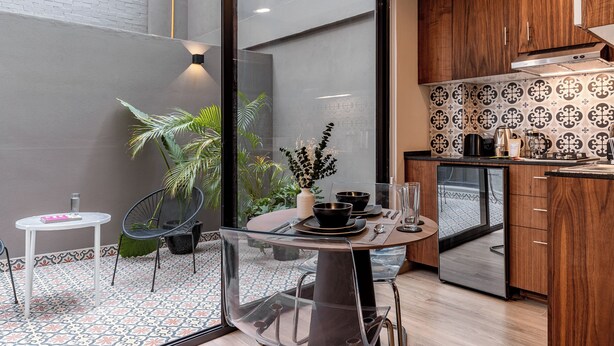 Una cocina moderna con refrigerador, armarios de madera y un comedor con mesa y sillas.