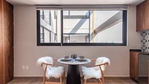 Cocina moderna con una mesa de comedor lista para cuatro personas, ventanas grandes y vistas al exterior.
