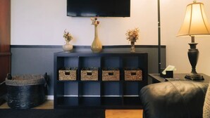 Una sala de estar con un televisor de pantalla plana, una lámpara y cajas de almacenamiento.