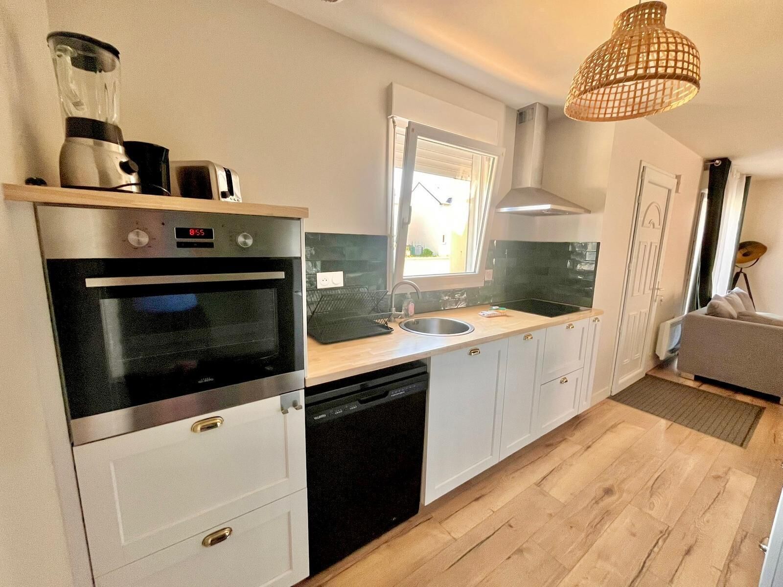 Eine moderne Küche mit Einbauofen, Geschirrspüler, Spüle und Fenster.