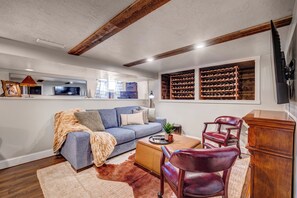 Ein Wohnzimmer mit Sofa, Couchtisch, Ledersessel, Fernseher und Weinkühler.