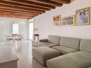 A living room with a sofa, a dining table with chairs, a chandelier, and framed pictures on the wall. - Charming Ground-Floor Apartment Near Basilica della Salute & Zattere Waterfront (Venezia)