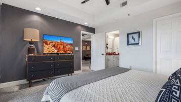 A bedroom with a bed, a dresser, a television, and a ceiling fan.