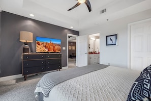 Ein Schlafzimmer mit Bett, Kommode, Fernseher und Deckenventilator.