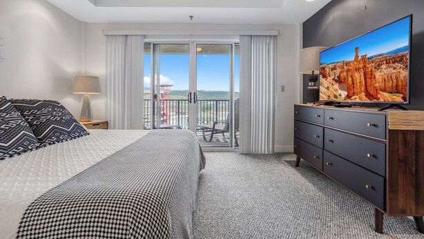 Une chambre d’hôtel avec un lit, une télévision, une commode et un balcon offrant une vue.