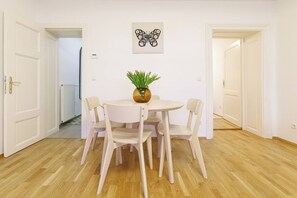 Ein Essbereich mit einem runden Tisch, vier Stühlen, einer Blumenvase und einem Wandbild.