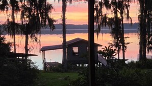 Uma cabana à beira do lago com varanda coberta, rodeada por árvores e vegeta ção.