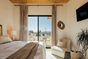 Une chambre avec un grand lit, un canapé, une télévision et une vue sur l’extérieur.
