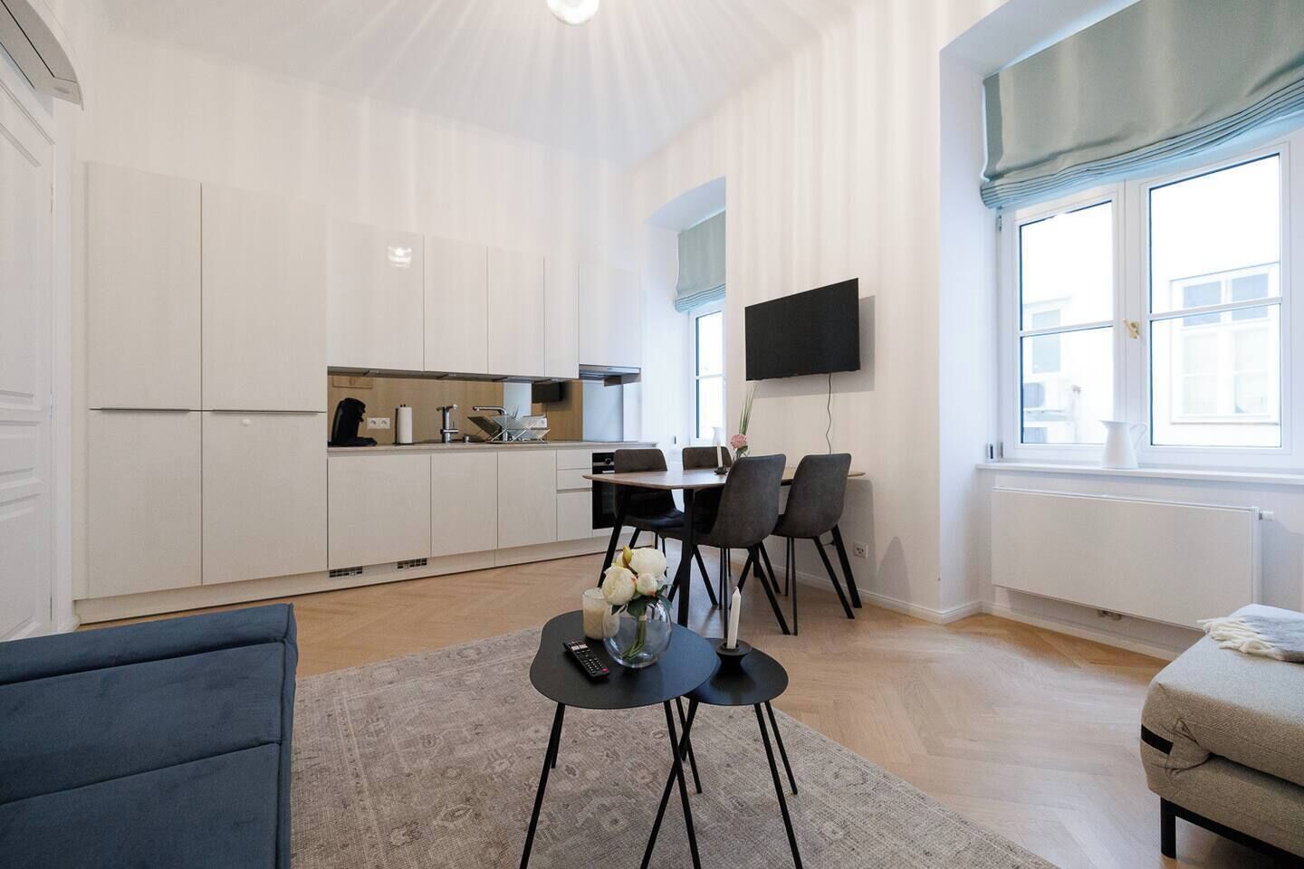 A modern living room with a sofa, a coffee table, and a dining area with chairs and a table.