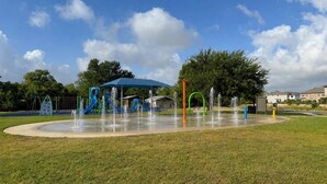 Ein Spielplatz mit einem Trinkbrunnen und einer überdachten Spielanlage.