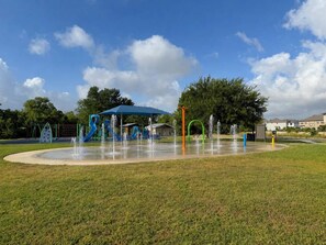 A playground with a water fountain area and a covered play structure.