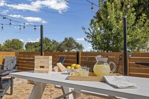 Een buitengebied met een gedekte tafel voor een maaltijd, inclusief houten blokken, citroenen, glazen en een kan limonade.