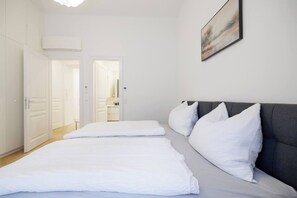 Ein Schlafzimmer mit Bett, Kissen, einem grauen Kopfteil und einem Bild an der Wand.