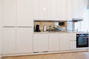 Eine moderne Küche mit weißen Schränken, einem Backofen und einer Kaffeemaschine.