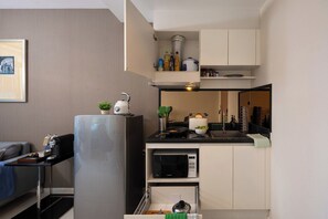 A compact kitchen with a refrigerator, microwave, and a small dining area. - Balcony & Kitchen · Pool, Gym, Fast Wi-Fi (Watthana)