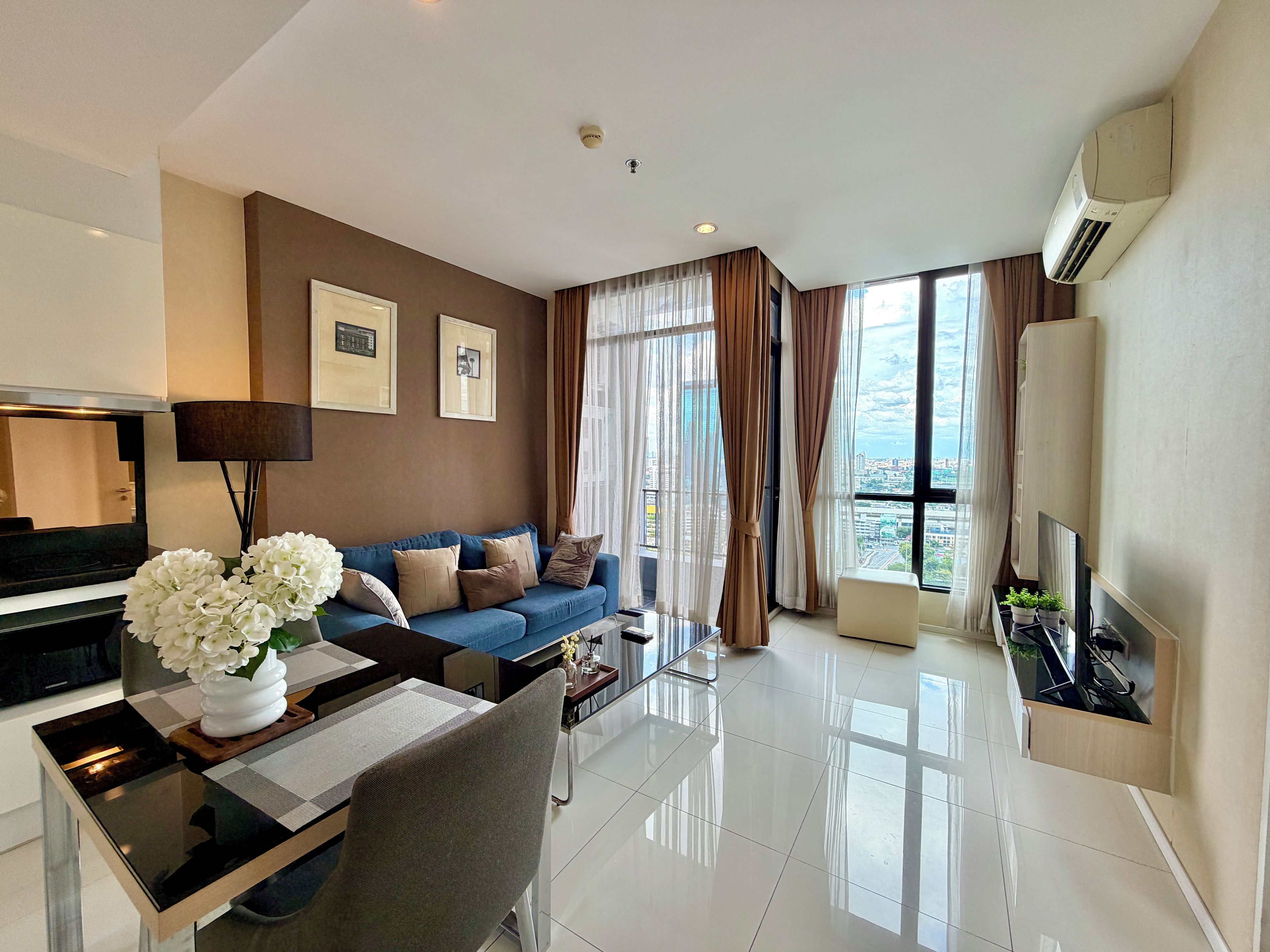 A modern living room with a sofa, a dining table, and a TV.