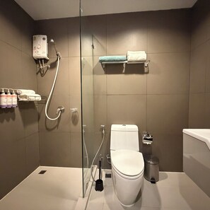A modern bathroom with a glass-enclosed shower, a toilet, a trash bin, and a towel rack. - Balcony & Kitchen · Pool, Gym, Fast Wi-Fi (Watthana)