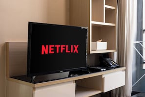 A hotel room with a television on a wooden desk, a remote control, and a telephone. - Balcony & Kitchen · Pool, Gym, Fast Wi-Fi (Watthana)