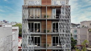 A multi-story building with balconies, wooden paneling, and the name 'Jungle Inn 448' visible. - New Apartments La Condesa by VIATO Homes (Ciudad de México)