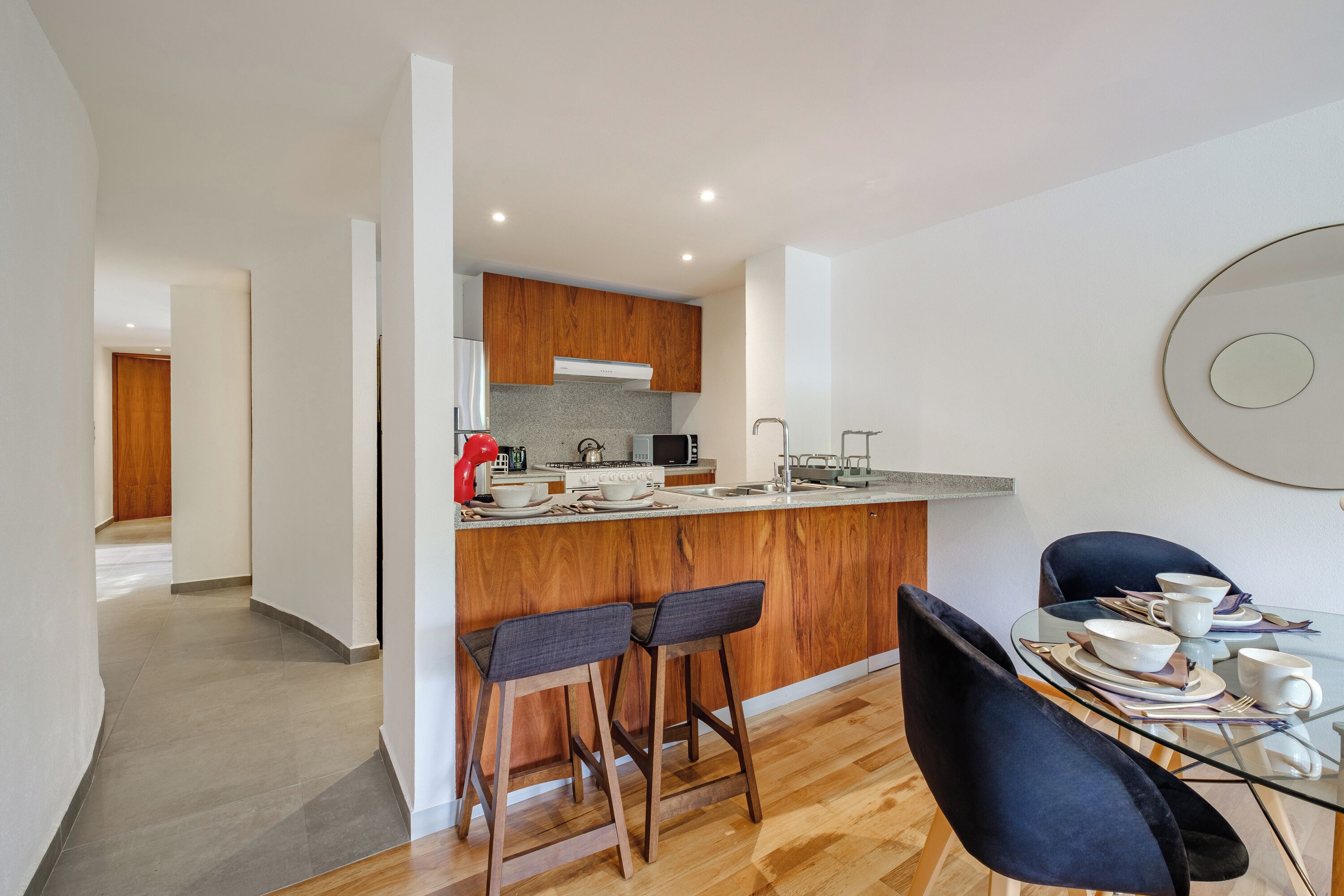 A modern kitchen with wooden cabinets, a glass island, and bar stools.