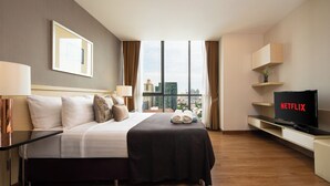 Una habitación de hotel con cama, televisión, ventana y vista a la ciudad, además de un escritorio.