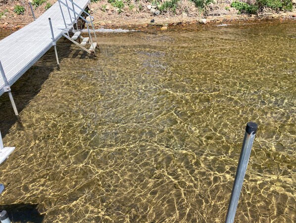 Un cuerpo de agua cristalina con un embarcadero de metal y escalones que bajan hacia él.
