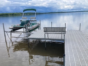 Um barco atracado num cais, com um banco e uma área de estar coberta.