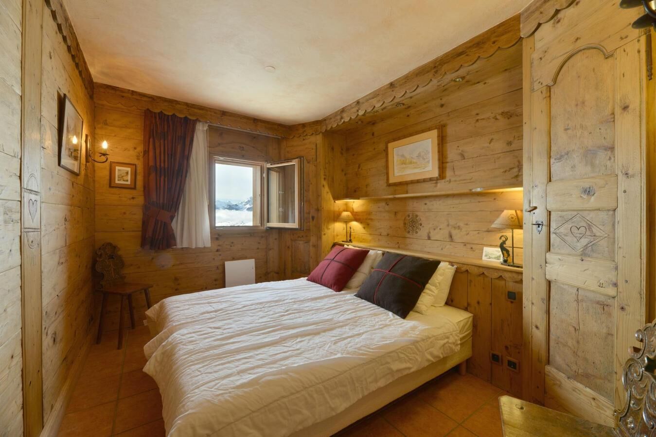 A wooden room with a bed, a window, a chair, and a lamp.