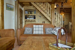 Ein gemütliches Wohnzimmer mit einer Holztreppe, einem Ledersofa und einem Couchtisch aus Holz.