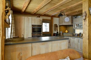 Eine rustikale Küche mit Holzsäulen, einem eingebauten Ofen und einer großen Kochinsel.