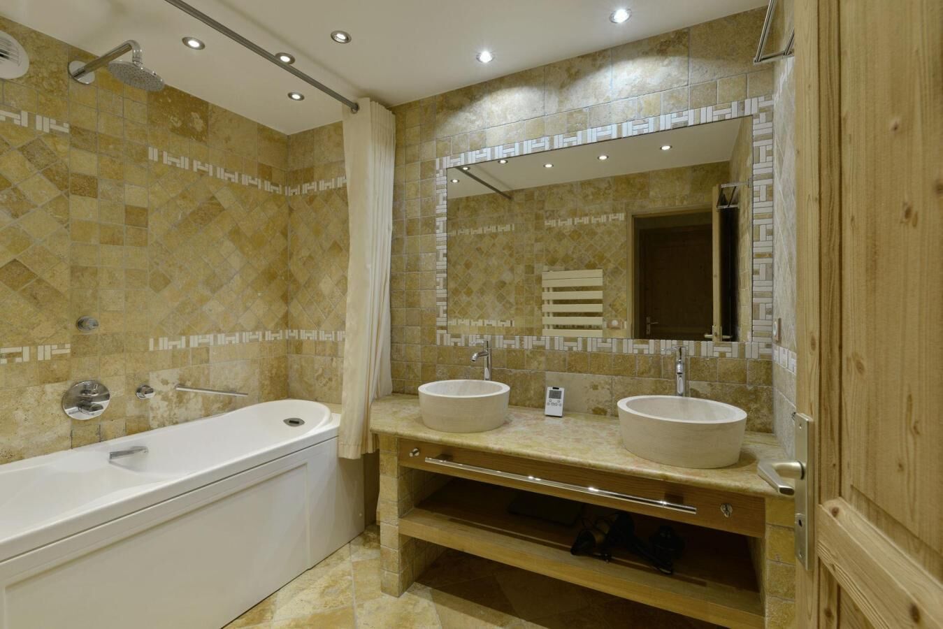 A bathroom with a bathtub, two sinks, a mirror, and a shower.